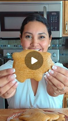 a woman holding up a piece of bread in front of her face and smiling at the camera