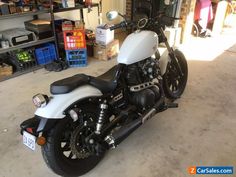 a white and black motorcycle parked in a garage next to a shelf filled with tools