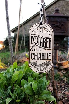 a sign that says potager and charlie hanging from a pole in front of some plants