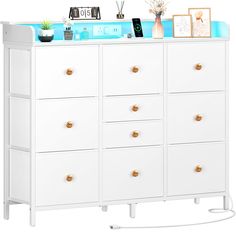 a white dresser with drawers and pictures on the top shelf, against a white background