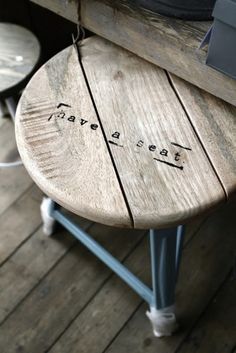 a wooden bench with writing on it sitting next to two stools and a table