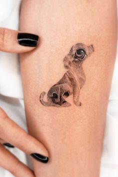 a woman's arm with a dog tattoo on it and her hand holding the leg