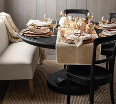 a dining room table with plates and glasses on top of it, next to a couch