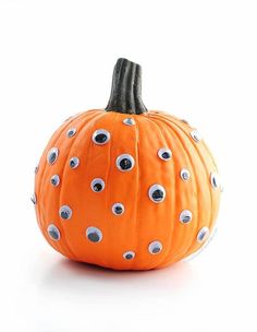 an orange pumpkin decorated with googly eyes and black tips on it's side