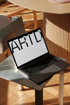 an open laptop computer sitting on top of a metal chair next to a wooden table