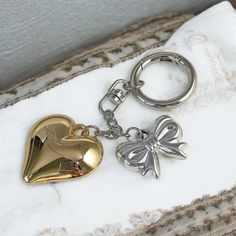 Elevate your accessory game with this Vintage Heart & Bow Chain Keychain, featuring a classic design in silver and gold tones. This elegant keychain combines a charming heart with a delicate bow, creating a timeless look that's perfect for any woman who appreciates vintage-inspired fashion. The combination of silver and gold colors adds a touch of sophistication, making it a versatile accessory for keys, bags, or as a decorative piece. Crafted with attention to detail, this keychain makes a thou Vintage Keychains, Elegant Keychain, Chain Keychain, Vintage Inspired Fashion, Gold Colors, Vintage Heart, Inspired Fashion, Stylish Gifts, Decorative Accessories