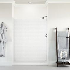 a bathroom with white walls and flooring has towels hanging on the shower stall door