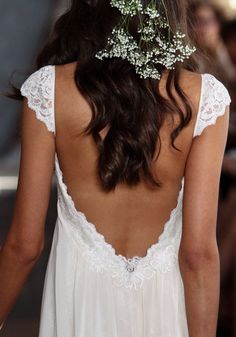 the back of a woman's dress with flowers in her hair and white lace