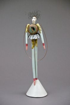 a white and green figurine is standing on top of a stand with wires attached to it