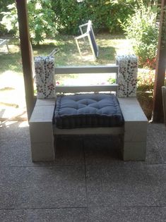 a bench made out of concrete with pillows on it