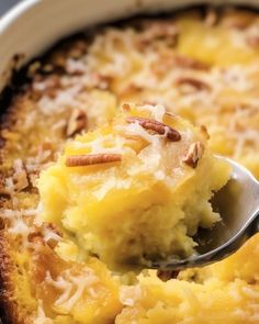 a spoonful of mashed potatoes with pecans on top in a casserole dish