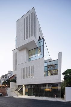 a white building with many windows on the top floor and bottom level, next to a street