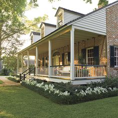 a house with porches and white flowers in the front yard