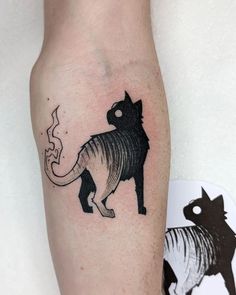 a black and white cat tattoo on the right leg, with an arrow in it's tail