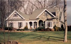 a house with white trim and windows in the front yard, surrounded by green grass