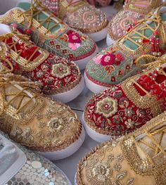 many different types of shoes on display for sale in a market stall, some decorated with gold and red flowers