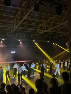 a group of people standing on top of a stage with yellow beams in the air