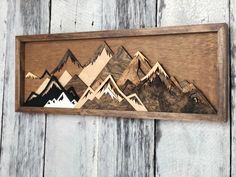 a wooden wall hanging with mountains on it