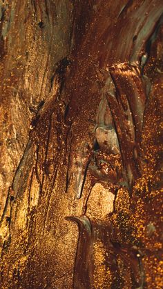 an abstract painting with gold and brown colors on the surface, as if it were liquid or water