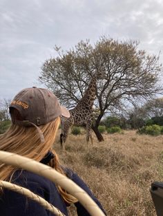 a giraffe standing next to a woman in a field