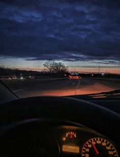 the dashboard of a car at night time with dark clouds in the sky above it