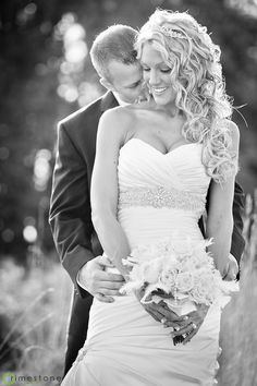 a bride and groom standing together in the grass