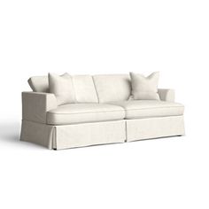 a white couch with four pillows on it's back and one arm facing the camera