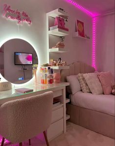 a room with a bed, desk and mirror in it's center area is lit up by pink lights