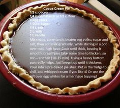 a chocolate cream pie sitting on top of a red plate next to a wooden table