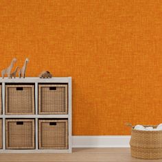 an orange wall with six baskets and two giraffe figurines on top