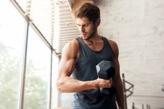 a man holding a black dumbbell in his right hand