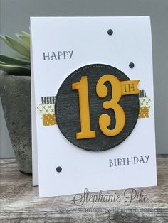 a birthday card with the number thirteen on it and a potted plant in the background