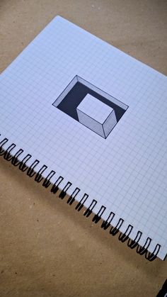 an open notebook with a square and rectangle design on the cover, sitting on a table