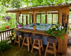 an outdoor hot tub on a deck with stools and flowers in the potted plants