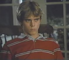 a young man sitting in a chair looking at the camera with an intense look on his face