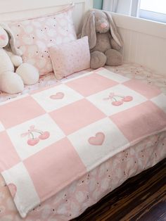 a pink and white checkered bedspread with two stuffed animals on the bed