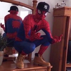 a spider man sitting on top of a dresser next to a mirror