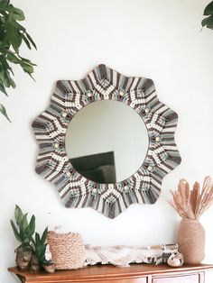 a mirror sitting on top of a wooden dresser next to a potted plant and vase