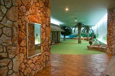 the inside of a building with stone walls and green carpeted flooring is shown