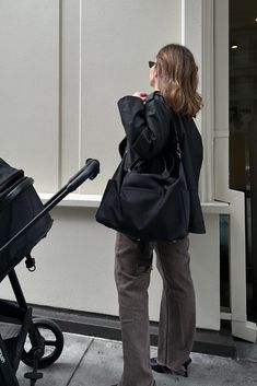 a woman standing next to a stroller and looking at the side of a building