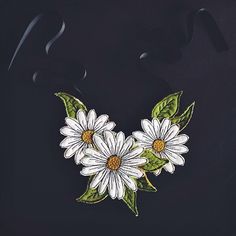 white daisies with green leaves on a black background are embroidered onto the back of a bag