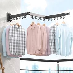 several shirts hanging on clothes racks in front of a window