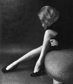 a black and white photo of a woman sitting on a chair with her legs crossed