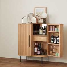 a wooden cabinet with bottles and glasses on it's shelf next to a wall