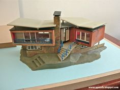 a model of a house sitting on top of a blue countertop next to a white wall