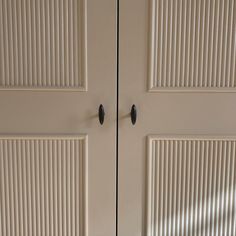 two white doors with black handles in a room