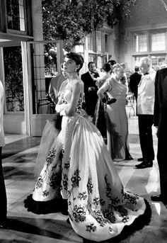 black and white photo of people in formal wear at an event with one woman wearing a gown