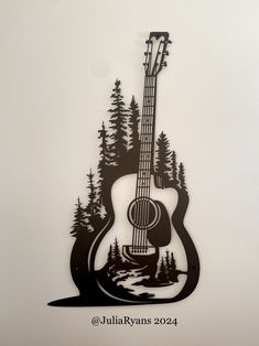 an acoustic guitar cut out of metal with trees and water in the backround