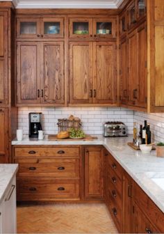 a kitchen with wooden cabinets and marble counter tops, along with white tile backsplash