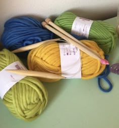 several balls of yarn and knitting needles on a table